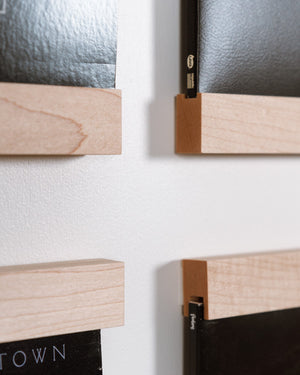 Close-up of Maple Drop-In Record Display shelves. Showing the grooves in the top and bottom pieces that hold the record on a white wall.